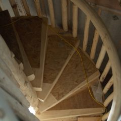 View downward of the curved spiral stair railing | Log Spiral Stairs | Handcrafted Wood LLC